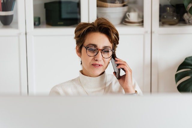 landlord with short hair and glasses talking on the phone while at their desk